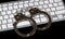 Keyboard and handcuffs with LED lights on. Cybercrime concept.