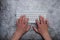 Keyboard with hands on a dark gray background. Asphalt concrete wallpaper. Context, writer, programmer, office work.