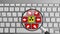 Keyboard with red and yellow virus theme buttons and magnifying glass