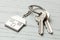 Keychain house and keys on white wooden background