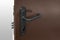 Keyhole and bolts at brown white door with black handle