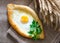 Khachapuri with egg and parsley on sackcloth, ears of wheat