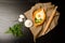 Khachapuri with eggs on sackcloth, flour, eggs and parsley on black table, space for text