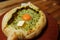 Khachapuri Made From a Delicious Tender Dough with Spinach, Melted Cheese and Butter Close Up. Traditional Hachapuri