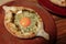 Khachapuri Made From a Delicious Tender Dough with Spinach, Melted Cheese and Butter Close Up. Traditional Hachapuri Topped with