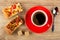 Khachapuri with tomato and basil, sugar cubes, cup with coffee on saucer, spoon on table. Top view