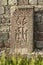 Khachkar standing at the old wall in a park located around the Geghard monastery located in the mountains of Armenia