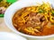 Khao Soi, Thai noodle curry soup with stewed meat of beef (khao soi nuer) in white bowl, close-up.