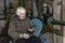 KHARKIV, UKRAINE- 3 MARCH 2022: elderly woman with phone sits on chair in basement and calling relatives, hiding from artillery
