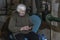 KHARKIV, UKRAINE- 3 MARCH 2022: elderly woman with phone sits on chair in basement, hiding from artillery shelling of residential