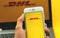 Kharkov, Ukraine - February 22, 2021: DHL app on screen of Apple smartphone, logo of shipping company, background