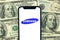 Kharkov, Ukraine - January 28, 2021: Samsung logo. Dollar bills background. Business company and money concept