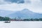 Khmer men and boy with old fishing boat going back home in the Praek Tuek Chhu River, cloudy over the Phnom Bokor mountain. Kampot