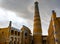 Khodja minaret and mosque madrasah in the historical center of Khiva with dark rain clouds, Uzbekistan
