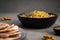 Kichari in a gray dish on a concrete surface next to condiments and tortillas