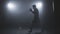 Kick boxer training in low light gym in slo-mo. Sportsman boxing in smoky gym