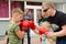 Kickboxing coach shows the boy how to make punch in sparring. Training outdoor in summer