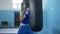 Kickboxing, fighter guy works out boxing hits on punching bag and trains arm muscles before match at sports studio