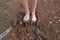 Kid bare foot with muddy feet on the rural road