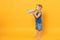 Kid boy 3-4 years old in blue beach summer clothes hold speak in megaphone isolated on bright yellow orange background