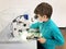 Kid boy conducts experiment with microscope in school lab. Curious inquisitive child learning physics and computer