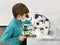 Kid boy conducts experiment with microscope in school lab. Curious inquisitive child learning physics and computer