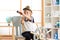 Kid boy dressed like a captain or sailor plays on chair as ship in his room. Child looks through telescope.