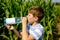 Kid boy drinking water from bottle on hot summer day in nature. Thirsty child.