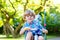 Kid boy driving tricycle or bicycle in garden