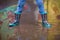 Kid boy in funny rubber boots standing in the puddle in the street after rain. Pair of colorful rubber boots ina puddle