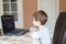 Kid boy with glasses playing online chess board game on computer