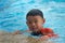 Kid or boy hold on swimming pool side bar to float during learning swimming class with happy face