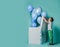 Kid boy holding box cover looks at blue balloons for birthday party flying out of big white box he has just opened