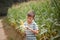 Kid boy holding and picking corn on farm in field, outdoors