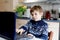 Kid boy learning at home on laptop for school. Elementary school child making homework and using notebook and modern