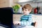 Kid boy learning at home on laptop for school. Elementary school child making homework and using notebook and modern