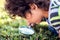 A kid boy looking through magnifier at plants. Children, discovery and botany concept