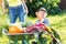 Kid boy and mother in domestic garden. Adorable child standing near the wheelbarrow with harvest. Healthy organic