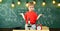 Kid boy near microscope, clock in classroom, chalkboard on background. First former confused with studying, learning