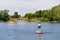 Kid boy paddling on sup board on a lake. Active child on modern trendy stand up paddle board. Summer outdoors vacations