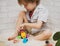 Kid boy playing with building blocks at home or kindergarten with bare feet on warm sheep`s clothing