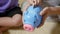 Kid boy preschool putting pin money coins into blue faced piglet slot