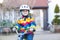 Kid boy in safety helmet and colorful raincoat riding bike, outd