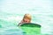 Kid boy swimming with surfboard on the beach on blue sea in summer. Blue ocean with wawes. Child boy swimming in sea.