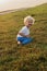 A kid boy three years old outdoors in august having fun falling on the grass at wildness