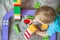 Kid boy toddler playing toys at home in multicolored construction set. Children`s games at home, child development in play, safe g