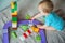 Kid boy toddler playing toys at home in multicolored construction set. Children`s games at home, child development in play, safe g