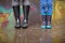 Kid boy and woman in funny rubber boots standing in the puddle in the street after rain. Family in colorful rubber boots