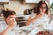 Kid brother and teen sister having breakfast at home in modern white kitchen and eating snacks