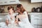 Kid brother and teen sister having breakfast at home in modern white kitchen and eating snacks